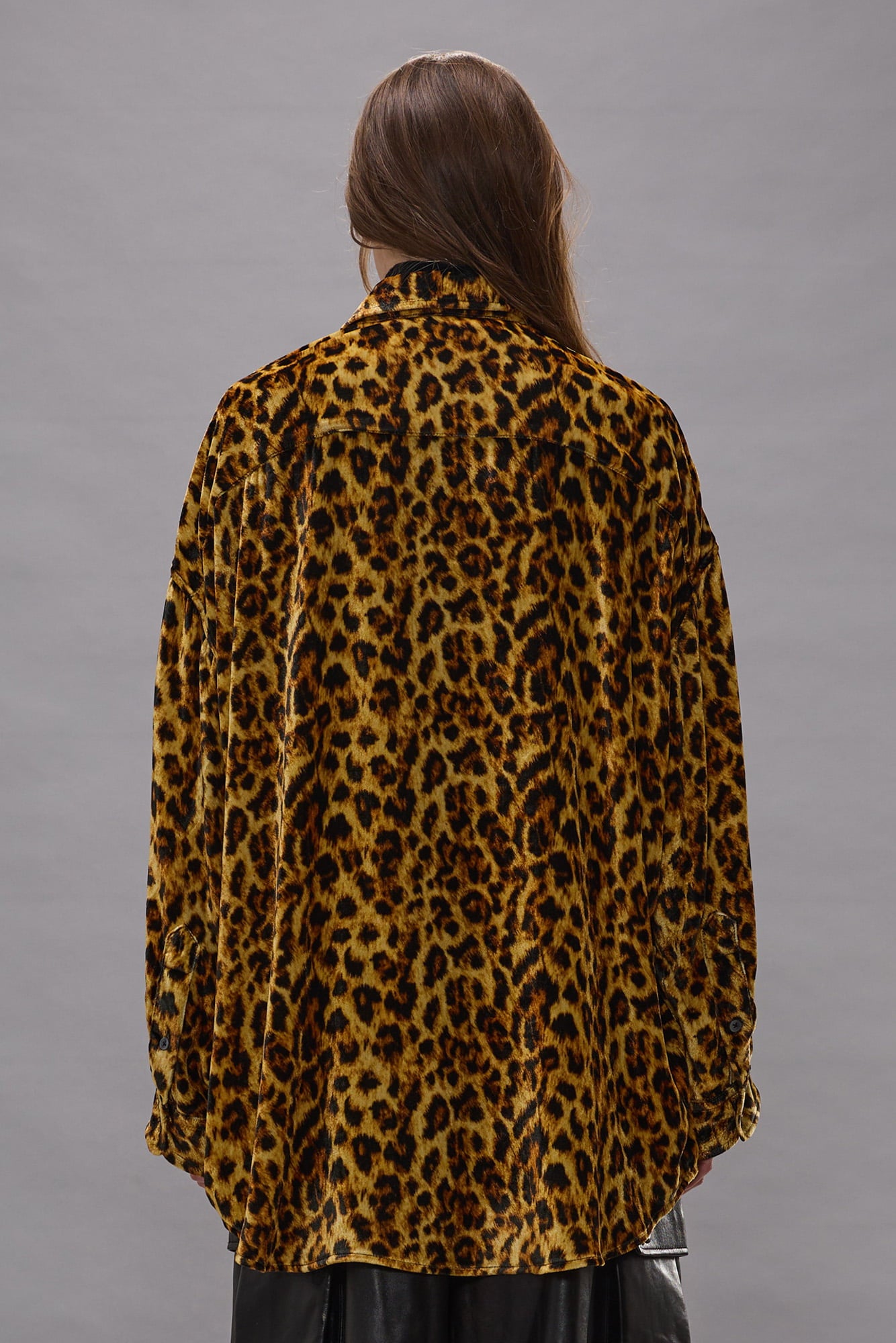 Light brown and black leopard print drop neck shirt displayed on model from back view.
