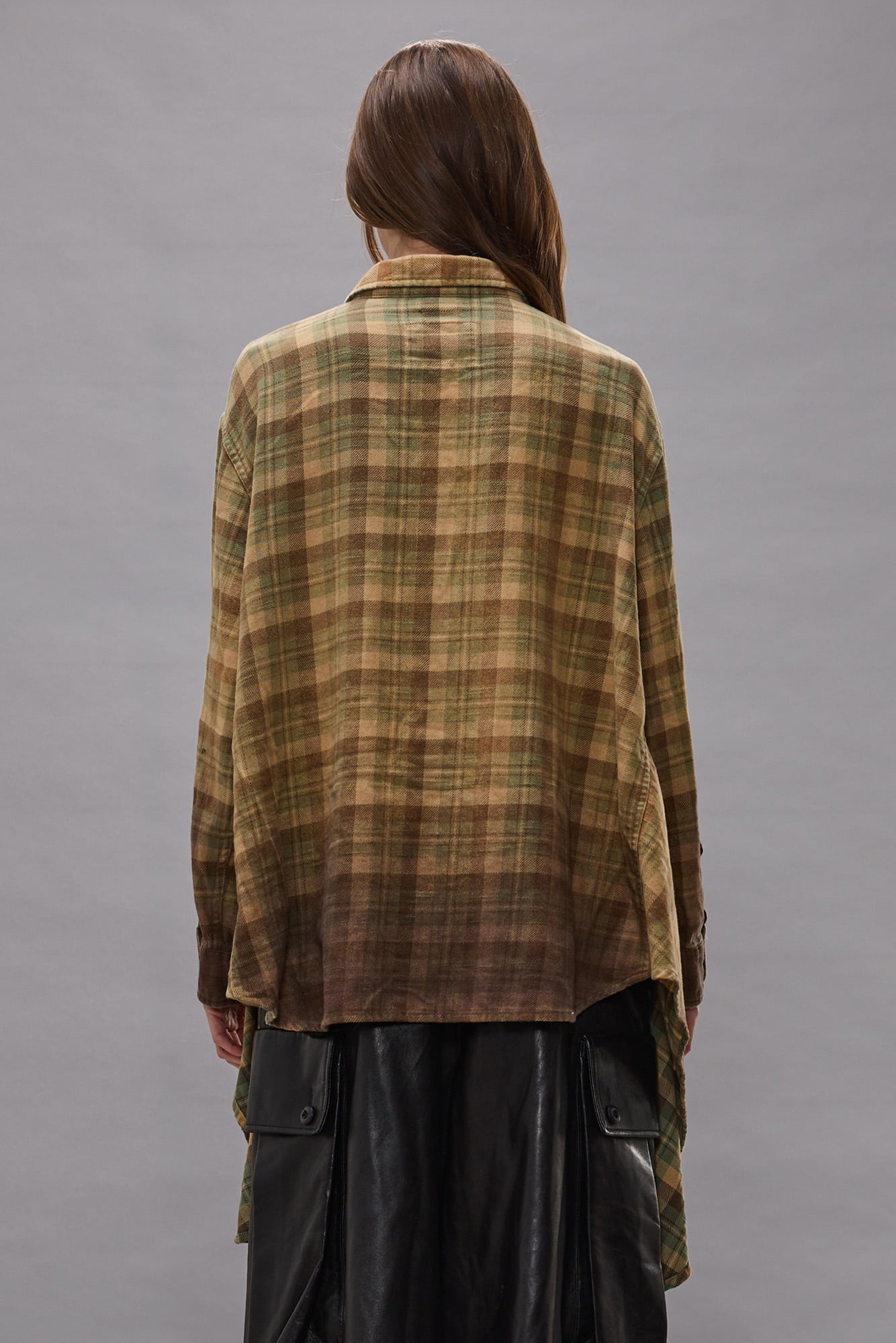 Plaid shirt in khaki and brown ombre tones with draped front, shown from back on model wearing black pants.
