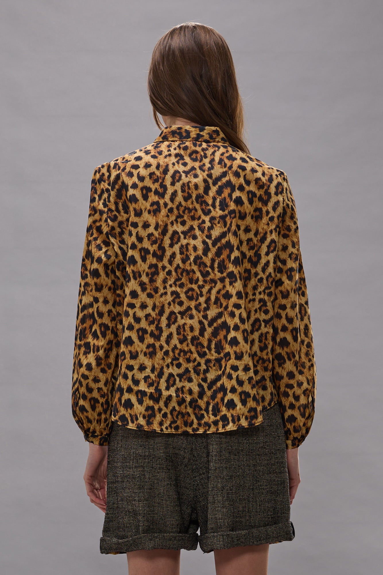 Yellow and black cheetah print blouse with ruffled long sleeves, shown from back on model.