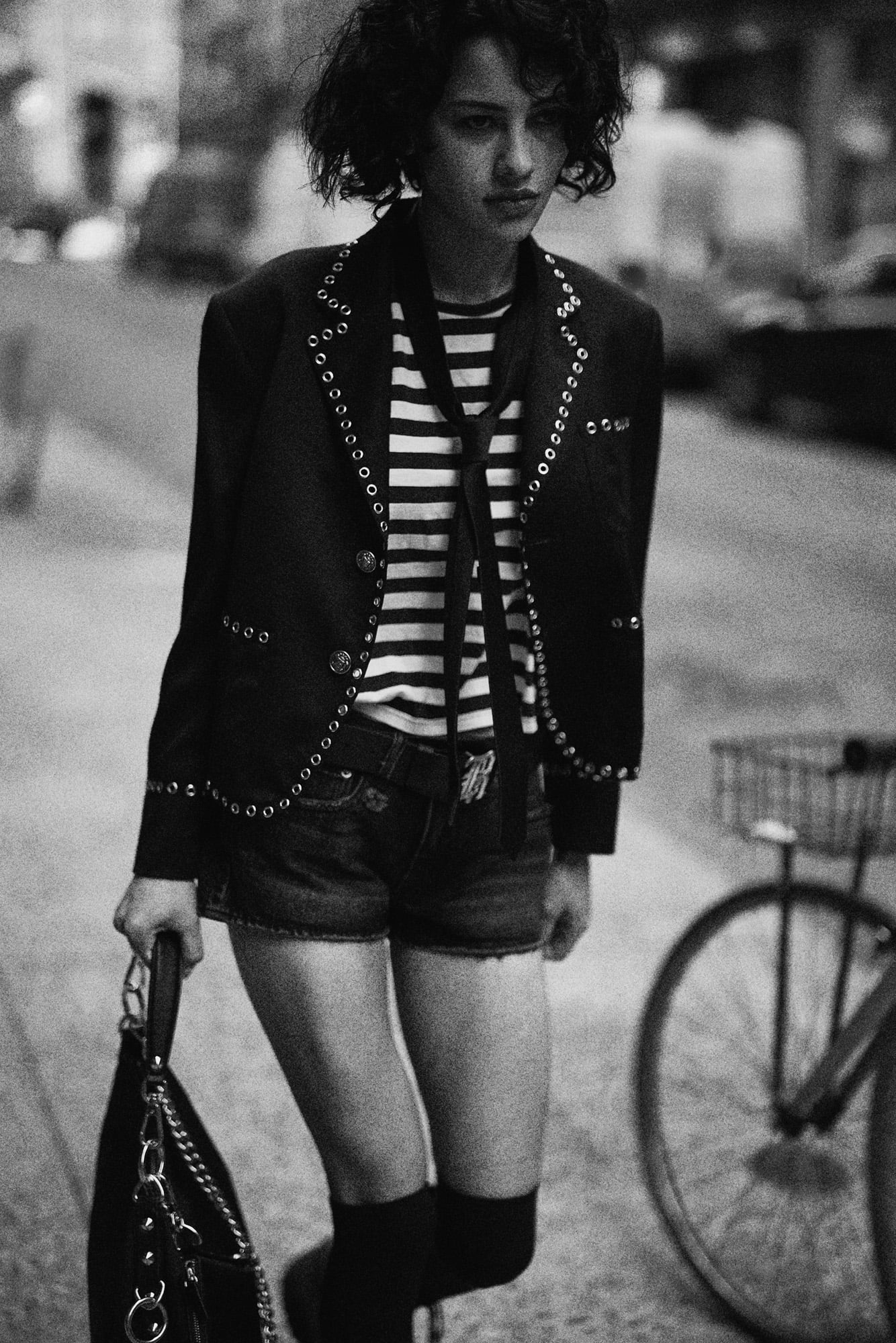 Black studded blazer layered over striped shirting with denim shorts