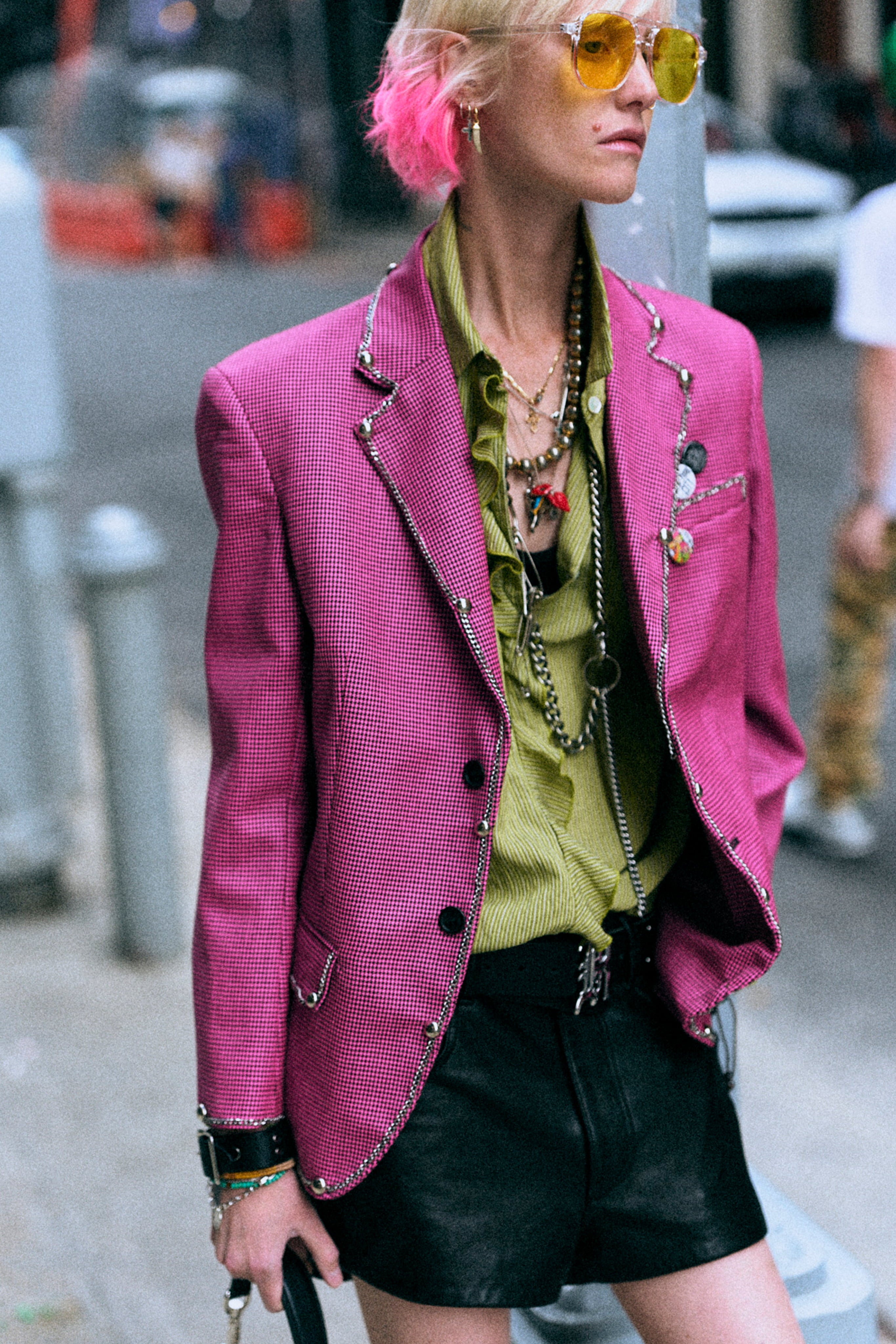 Model in pink blazer and black shorts with layered necklaces.