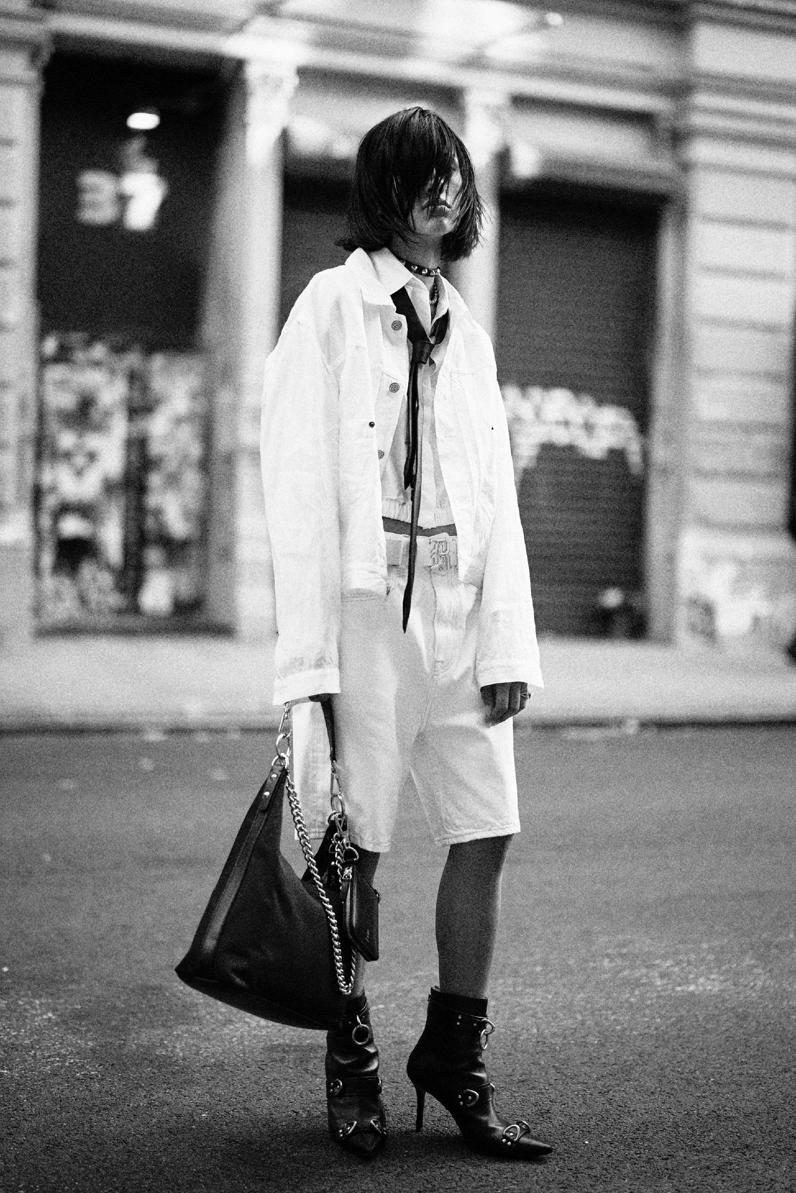 White jacket layered over shirt and shorts with chain strap bag